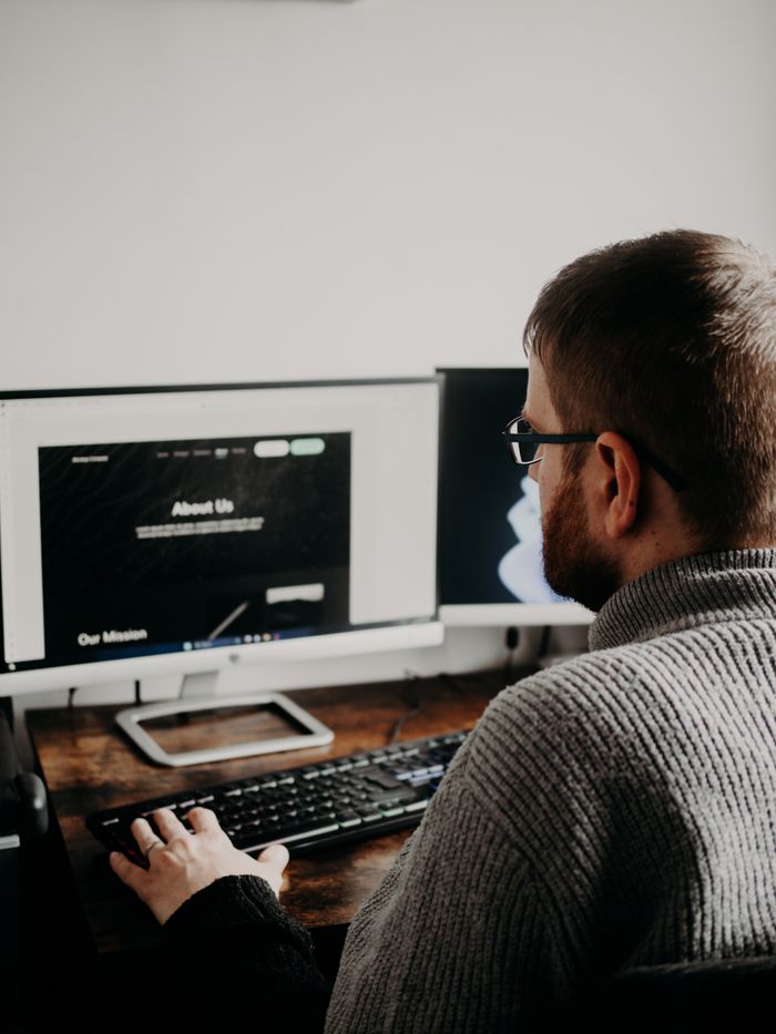 Mastering the First Impression: Your intriguing post title goes here Man working on web design at home office setup with dual monitors.